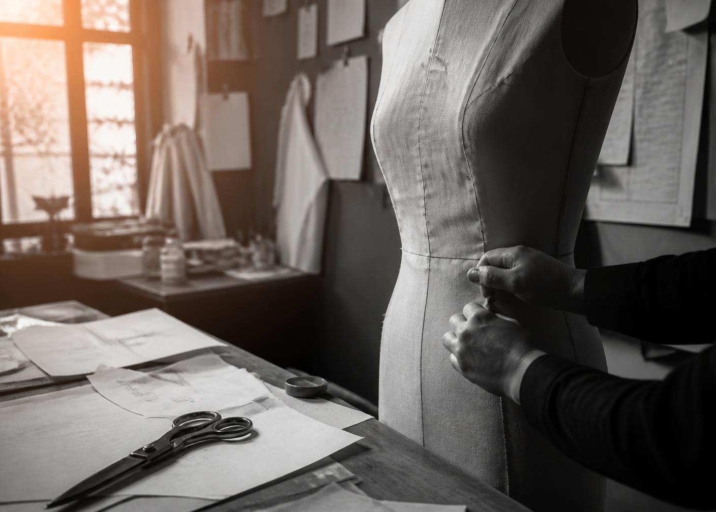 Hands pinning muslin on a dress form in the CoutureLine atelier